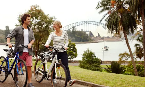 two individuals walking alongside their bikes and enjoying the view of the Harbour as part of the corporate and incentive program experience