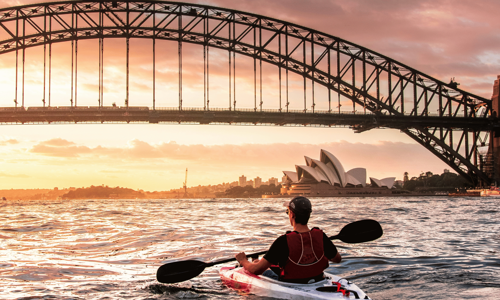 Individual kayaking on Sydney harbour with Bridge and Opera House in background
