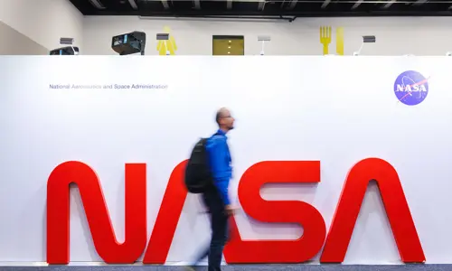 International Astronautical Congress 2025 Attendee Walking across a large NASA Sign
