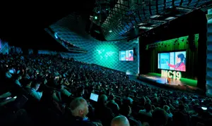 Audience seated in an auditorium watching a presentation at IMC19