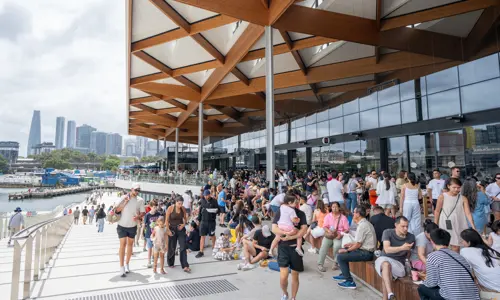 Busy outdoor promenade at the new Sydney Fish Market redevelopment with city skyline view