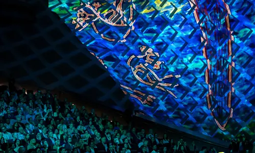 Theatre of conference attendees admiring First Nations digital artwork on a large immersive screen at the ICC Sydney