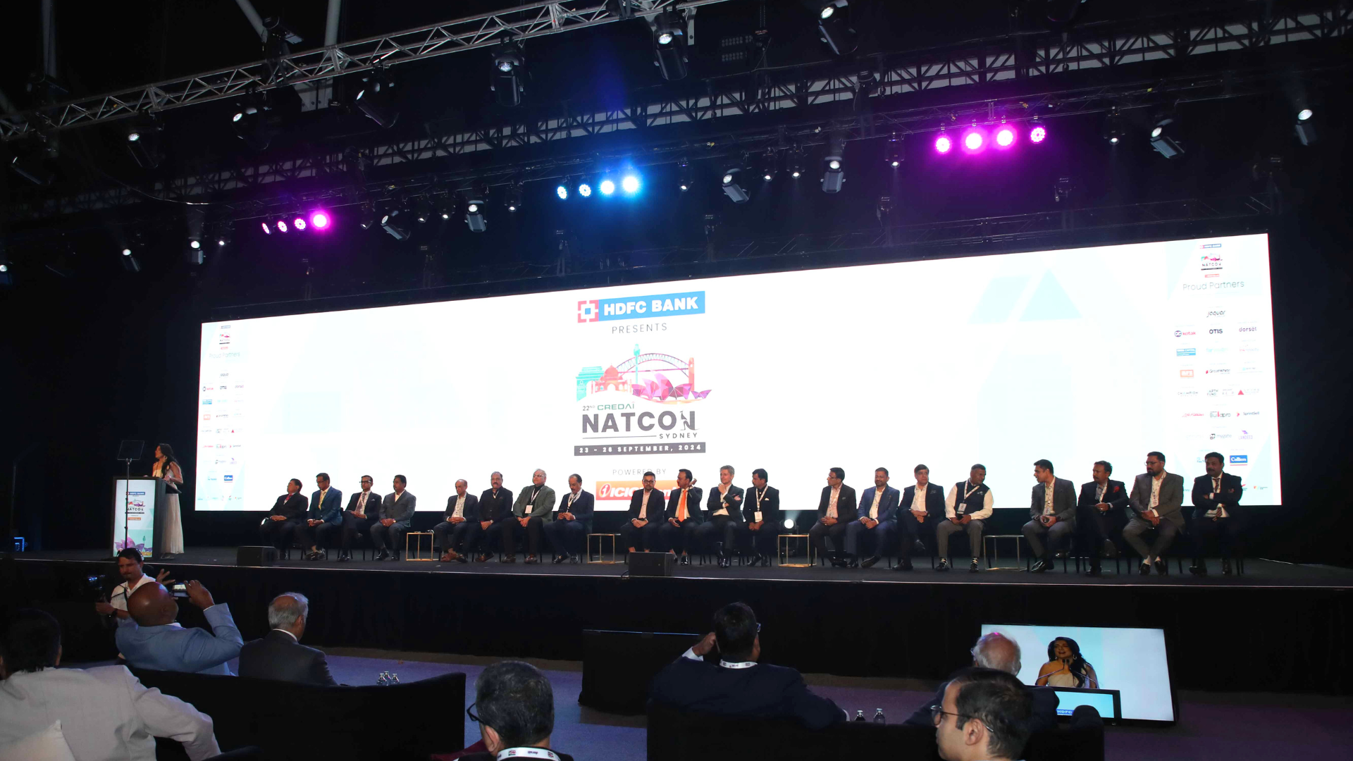 Panel of guests seated on stage during a presentation at the Credai Natcon event