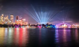 Night view of the Sydney CBD illuminated during Vivid, with light beams radiating over the harbour