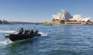 Delegates travelling by high-speed boat across Sydney Harbour with Sydney Opera House in the background